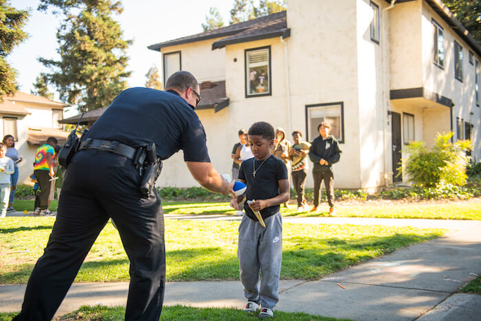 Police officer giving toys to a child outdoors in Fairfield, California