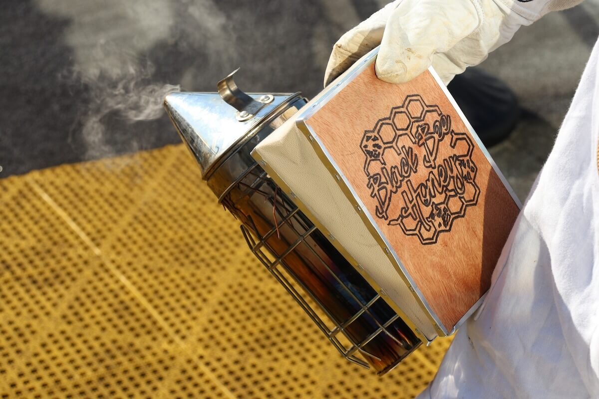 photo of a beekeeper holding equipment for the Orlando Black Bee Honey program
